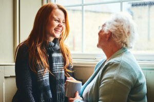 Young caregiver talking to senior woman about the benefits of home health care.