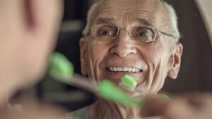 senior man maintaining healthy teeth and gums by brushing teeth