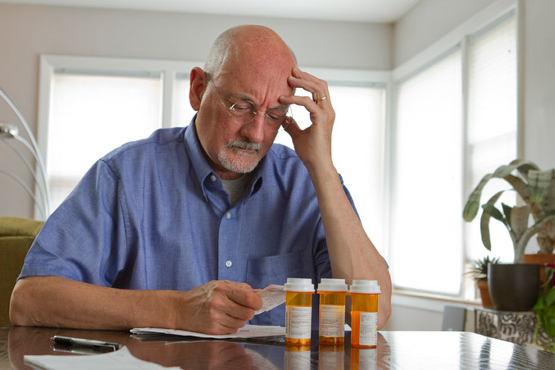 A man reviews his list of medications to see if he takes any drugs that elevate fall risk.