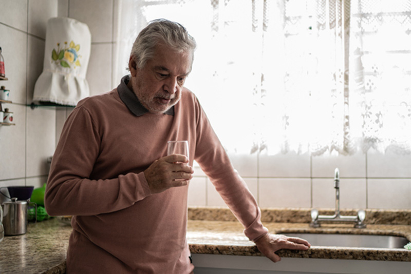 A man stands in the kitchen wondering about the signs of depression after a heart attack.