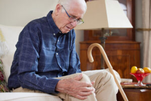 An older man who is getting a joint replaced massages his sore knee.